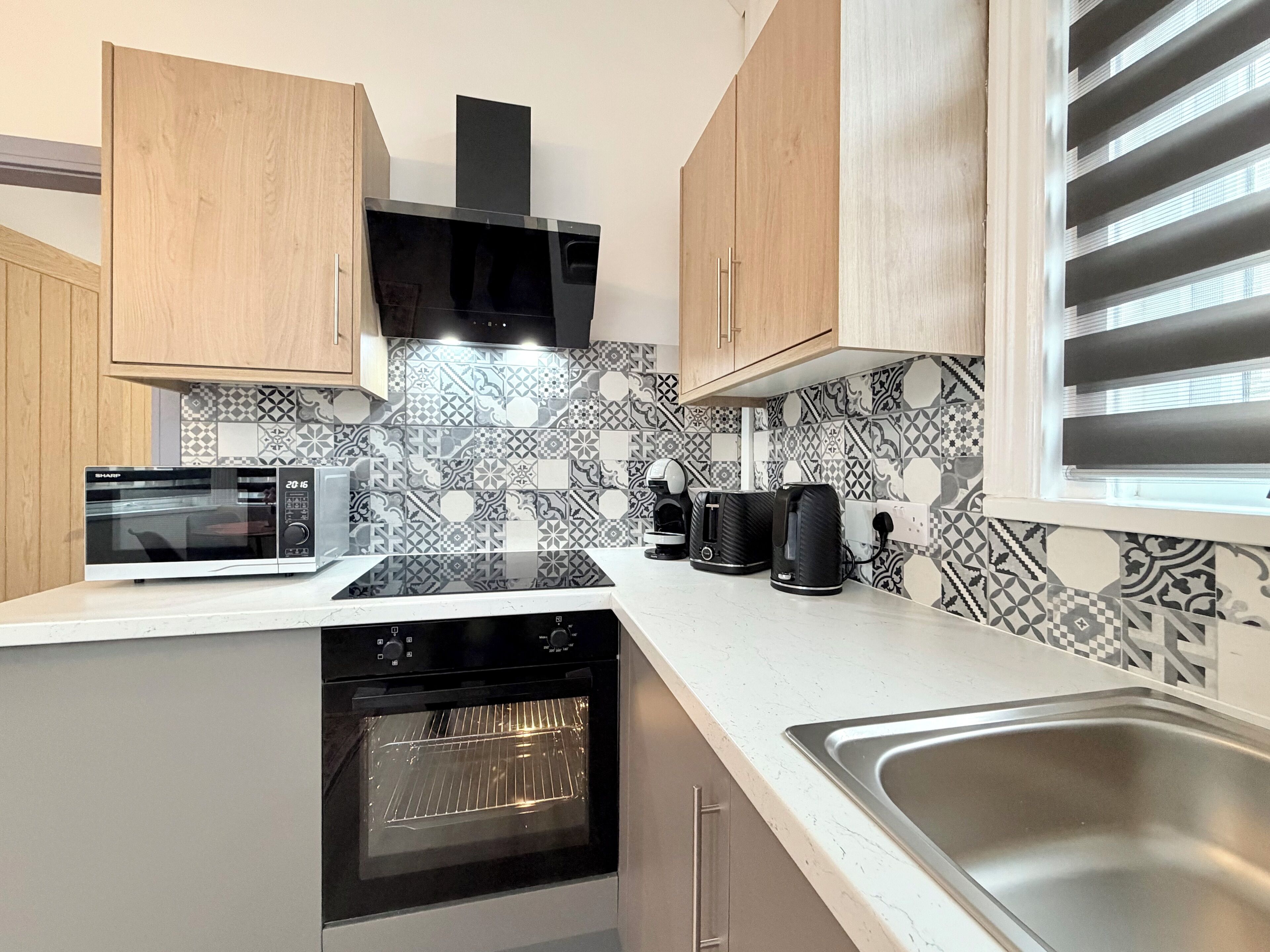 Cozinha moderna com micro-ondas, forno e cafeteira na bancada.