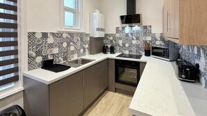 A compact kitchen with a built-in oven, a microwave, and a coffee maker. - Humberside Apartments (Cleethorpes)