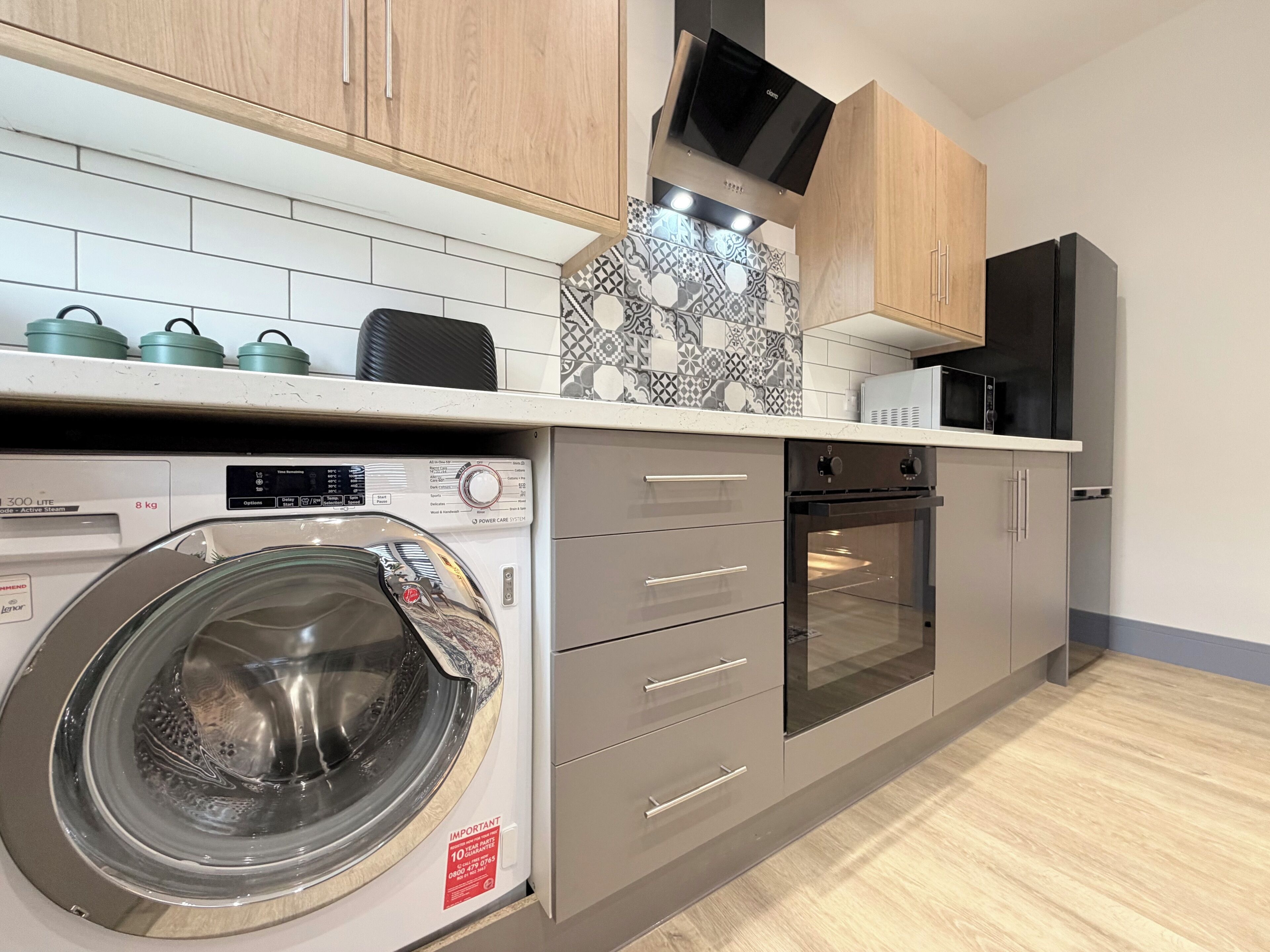 A modern kitchen with a built-in washer, oven, and microwave.