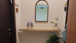 Un baño con espejo, estante con plantas, una maceta y una puerta.