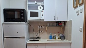 Una cocina compacta con refrigerador, microondas y un área pequeña con lavamanos.