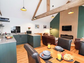 A modern kitchen with a dining area, wooden beams, and a flat-screen TV. - The Homestead (Saltburn-by-the-Sea)