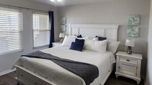 A bedroom with a bed, nightstands, a ceiling fan, and artwork on the walls. - Sunrise Villa #204 Close to Beach (Port Aransas)