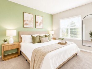 A bedroom with a bed, nightstands, a mirror, and artwork on the wall.