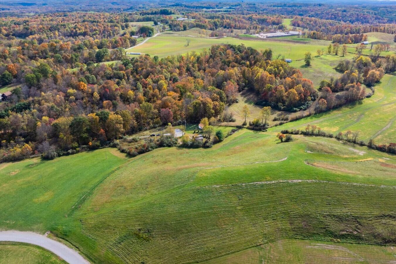 Vista aérea de un paisaje rural con campos, árboles y edificios dispersos.