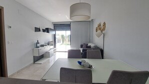 Een moderne keuken met een eethoek, met een witte tafel, grijze stoelen en een hanglamp.