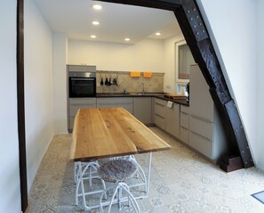 Eine moderne Küche mit einem Holztisch, weißen Hocker und Fliesenboden mit Muster.