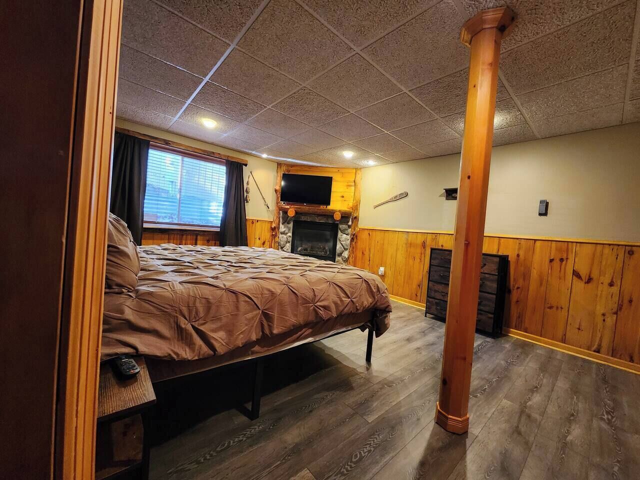 Ein Schlafzimmer mit einem großen Bett, Holzwänden, einem Kamin und einem Fernseher.