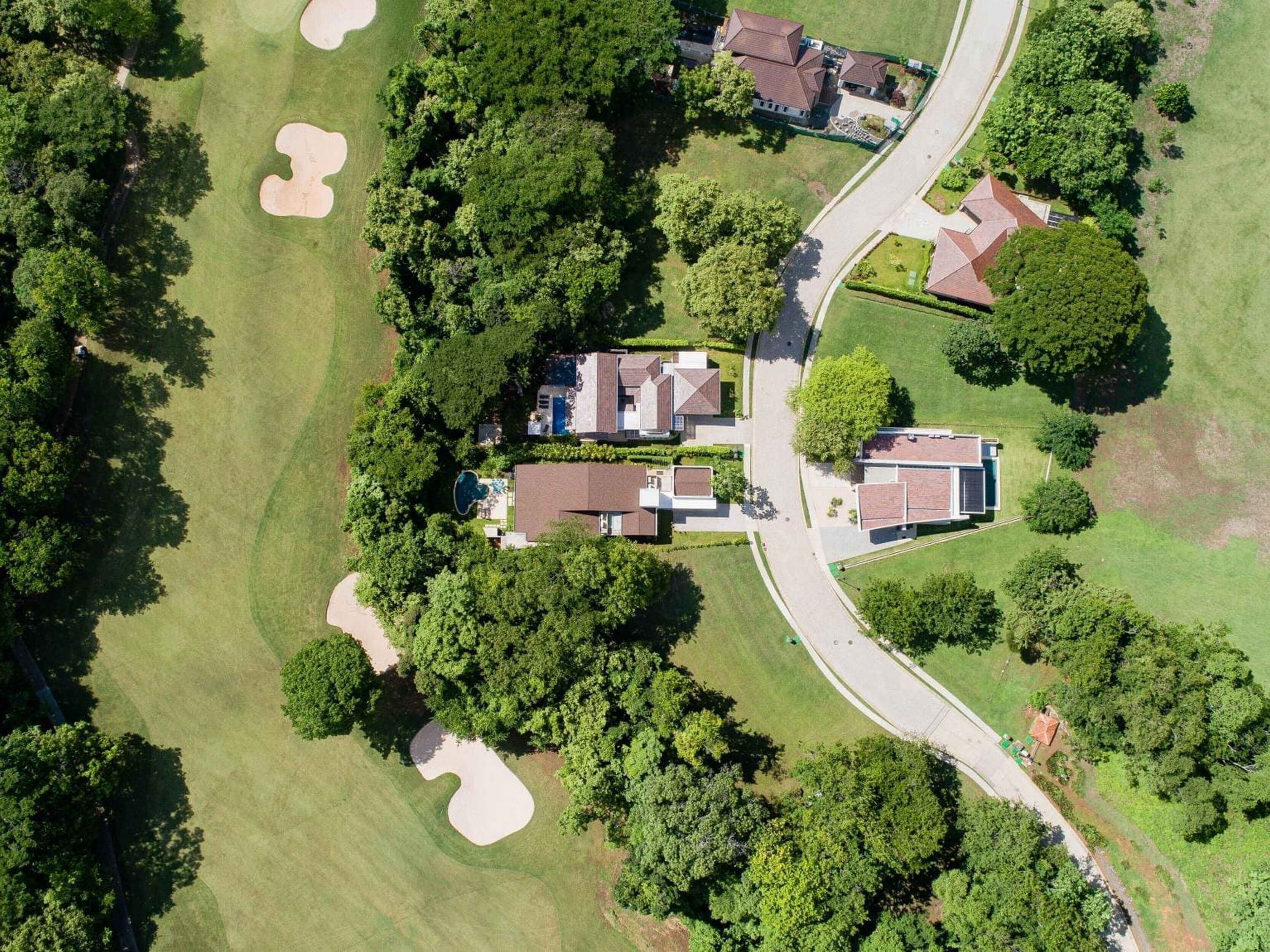 An aerial view of a residential area with houses, a golf course, and a road.