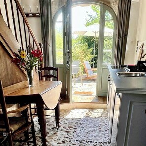 Ein Essbereich mit einem Holztisch und Stühlen, einer Blumenvase und Blick auf die Terrasse durch eine Glastür.