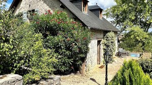 A stone house with a sloped roof, surrounded by lush greenery and a clear blue sky. - La Blanchie Haute, Gîte de charme d'exception pour 2 en Vallée de la Dordogne (Martel)