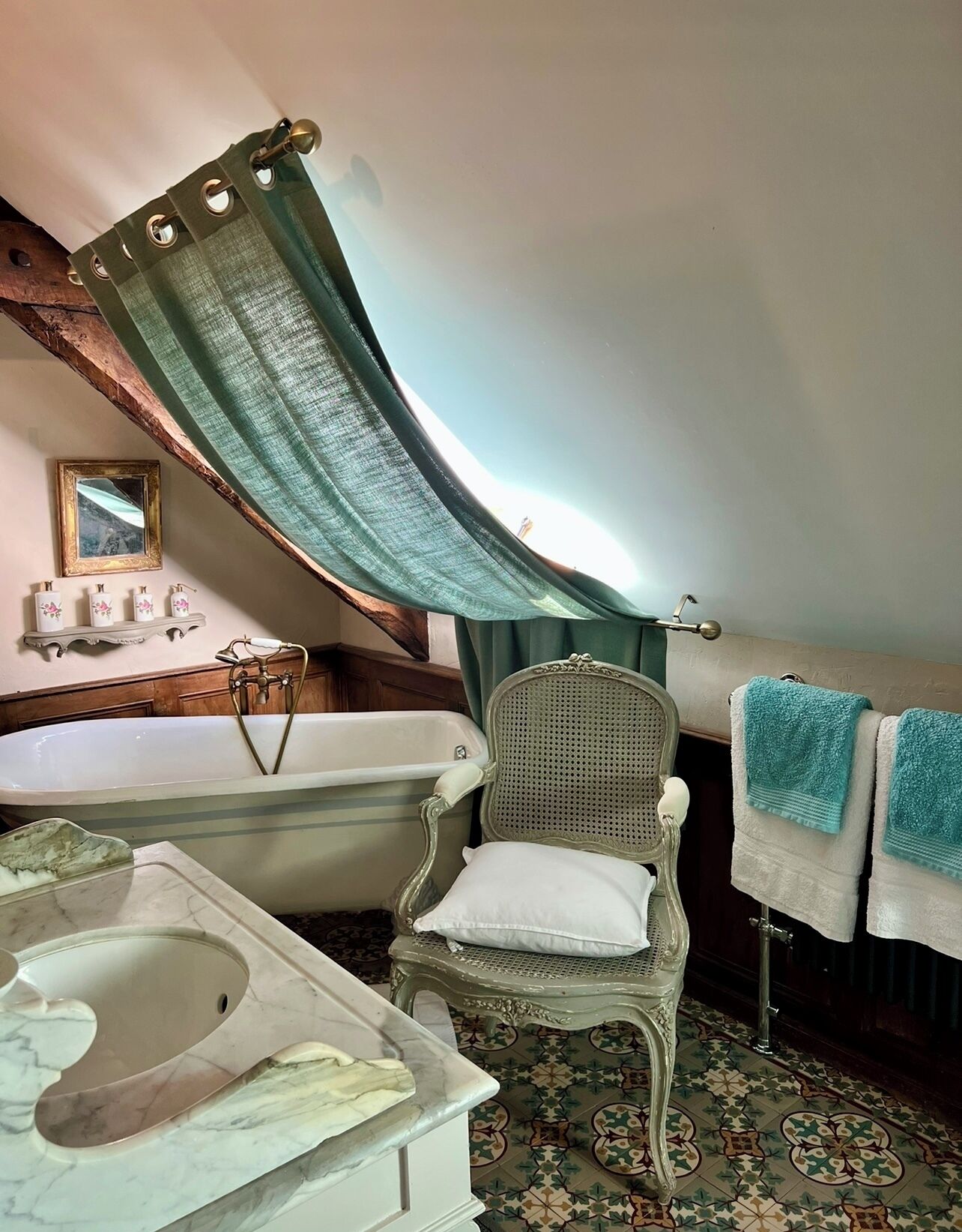 A bathroom with a bathtub, a wooden chair, a toilet, and a mirror.