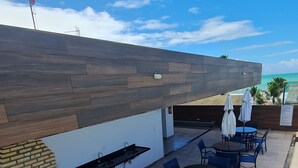 An outdoor patio with a brick oven, seating area, and a view of the ocean. - A 2  minutos do Mar  02PP by La Playa (Ipojuca)