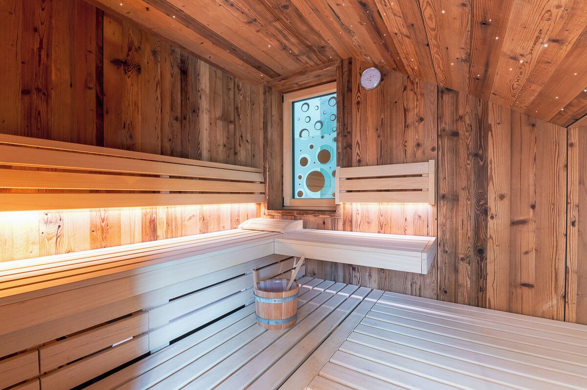 Een houten sauna met banken en een raam met ronde uitsparingen.