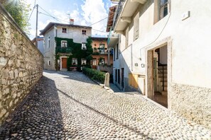 A narrow cobblestone street flanked by stone walls and buildings with balconies, suggesting a historic or traditional setting. - Lilliput Tiny Studio (Bellagio)