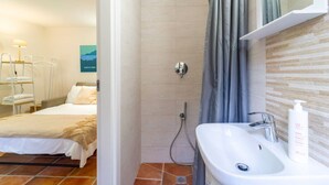 Een hotelkamer met een bed, een douche en een wastafel.
