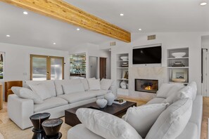 A modern living room with a white sofa, a coffee table, and a fireplace. - The Dean - Modern Zen Retreat in Deepwell (Palm Springs)