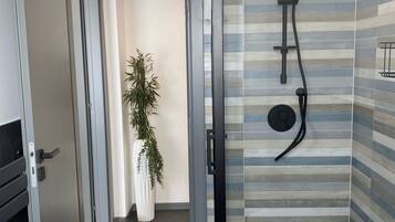 Un bagno moderno con doccia, piastrelle a righe e una pianta in vaso.