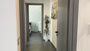 En moderne gang med en potteplante, et billede og en dør, der fører til et andet rum.