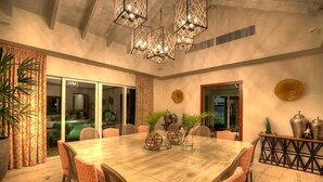 Un comedor amplio con una gran mesa de madera, sillas estampadas y jarrones decorativos.