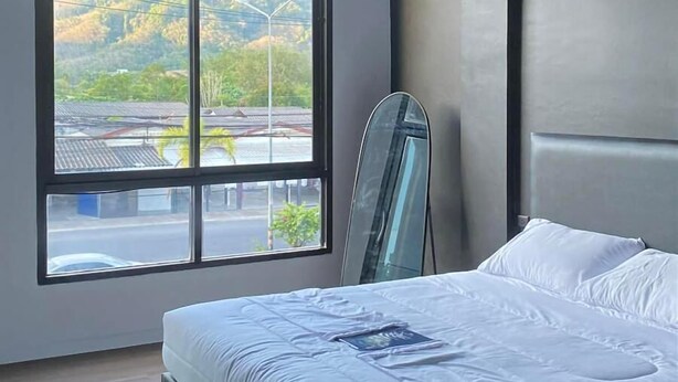 Une chambre à coucher moderne avec une grande fenêtre, un lit et un miroir.