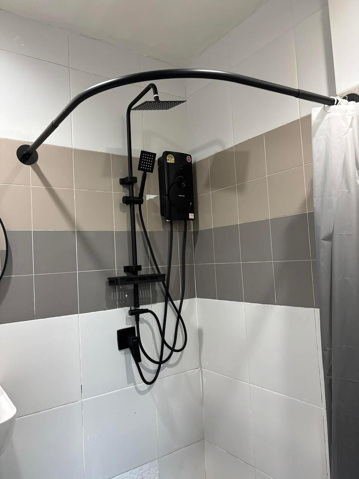 A shower area with a handheld showerhead, a wall-mounted control panel, and a shower curtain.