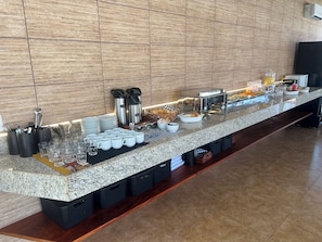 A breakfast buffet setup with various food items, utensils, and containers. - Pousada Verde Serrath (Mangaratiba)