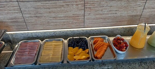 A buffet with various food items including meats, cheeses, fruits, and a beverage. - Pousada Verde Serrath (Mangaratiba)