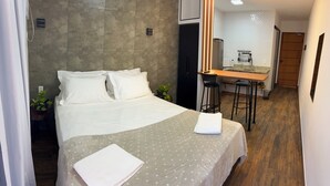 A hotel room with a bed, a small desk, and a kitchenette. - Pousada Verde Serrath (Mangaratiba)