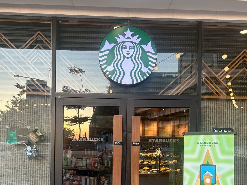 Ein Starbucks Geschäft mit gut sichtbarem Logo, Bestellknöpfen und einem Plakat zur Kundenbindung.