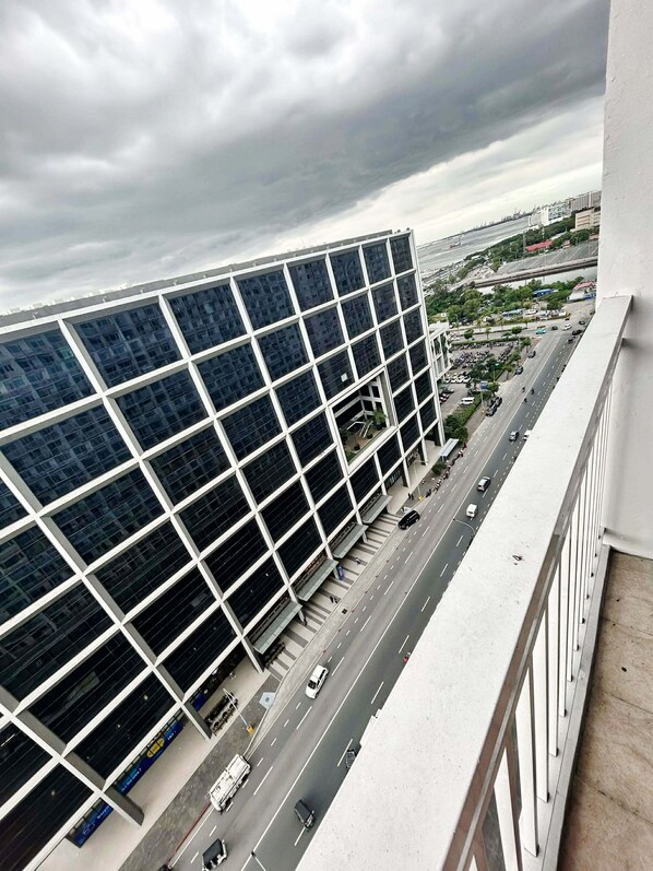 A modern building with a grid of windows, a busy street below, and a cloudy sky. - Shore Residences MOA staycation (Pasay)