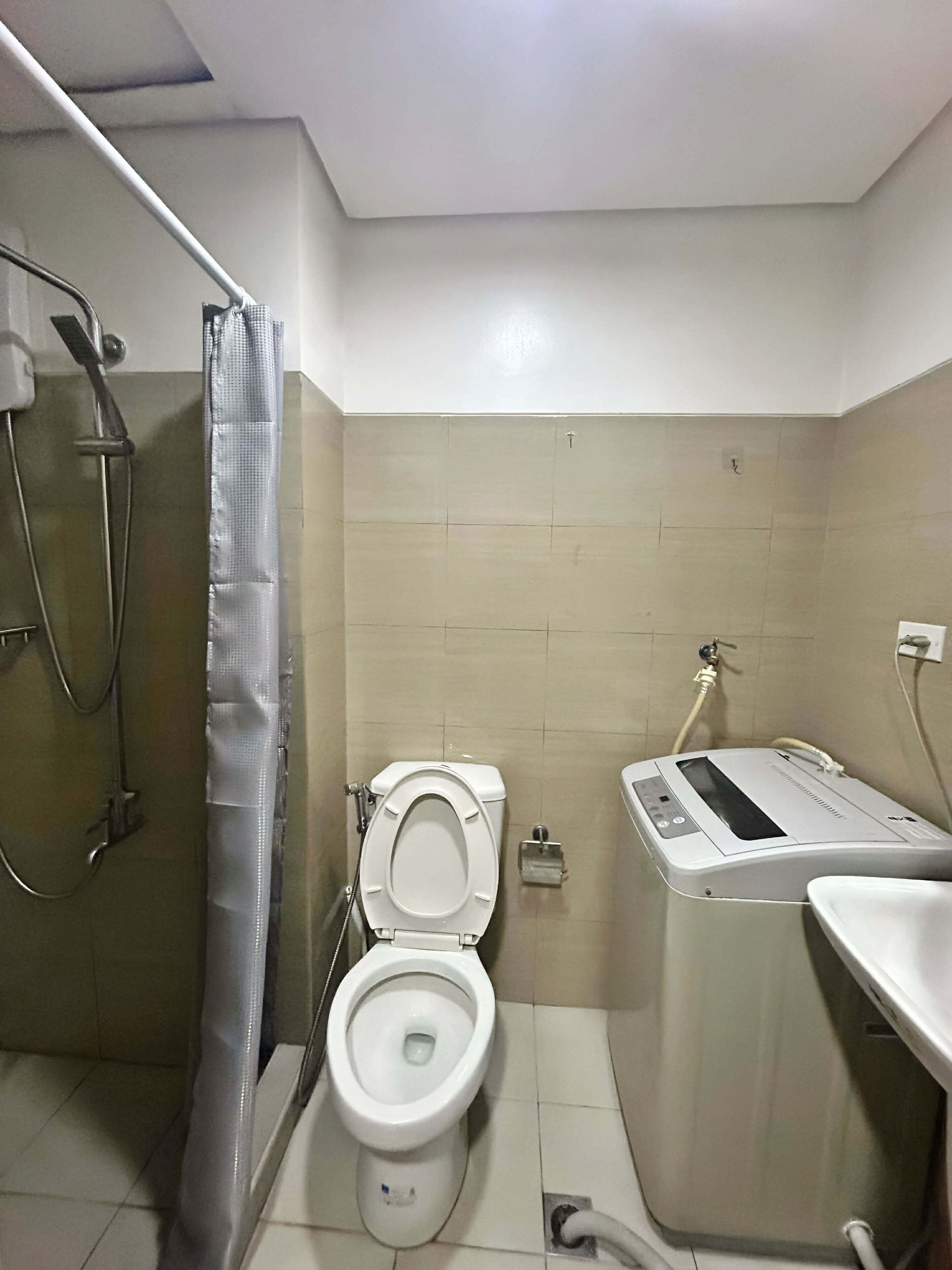 A modern bathroom with a toilet, shower, and a water heater.