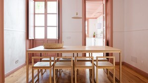 Un grand espace dédié à la salle à manger, avec une longue table en bois et six chaises. On y trouve un panier sur la table, et la pièce est dotée d’un plancher en bois et de murs peints en rose.