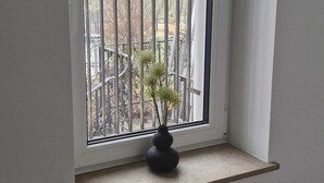 Et vindue med en metalgitter, en lille hylde nedenunder og en sort hængende lampe.
