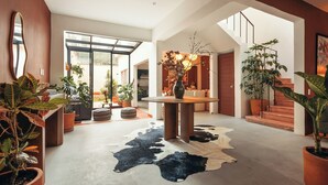A spacious interior with a central round table, a cowhide rug, and multiple potted plants. - Saltillo Condesa House (Ciudad de México)