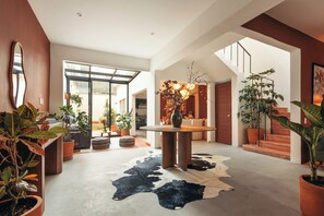 A spacious interior with a central round table, a cowhide rug, and multiple potted plants. - Saltillo Condesa House (Ciudad de México)