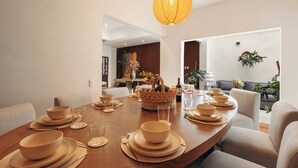 A dining area with a wooden table set for a meal, a woven basket with fruits, and a hanging lantern. - Saltillo Condesa House (Ciudad de México)