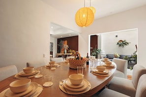 A dining area with a wooden table set for a meal, a woven basket with fruits, and a hanging lantern. - Saltillo Condesa House (Ciudad de México)