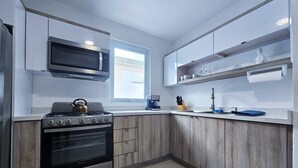 Een moderne keuken met een gasfornuis, oven, magnetron en houten kastjes.