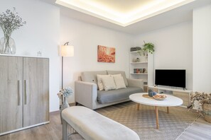 Ein modernes Wohnzimmer mit einer Couch, einem Couchtisch, einem Fernseher, einem Schrank und einem Bücherregal.