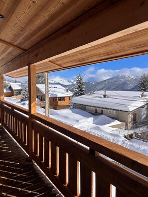 Ein Holzbalkon mit Blick auf schneebedeckte Häuser und Berge.