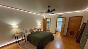 A bedroom with a bed, bedside tables, a lamp, a ceiling fan, and a walk-in closet.