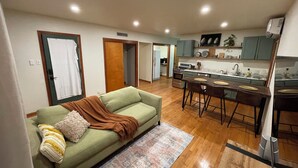 A modern apartment with a living room, dining area, and kitchen.