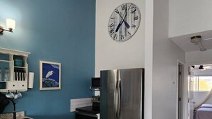 A modern kitchen with a stainless steel refrigerator, a clock on the wall, and a blue accent wall. - Cozy 1-bedroom condo in serene Oak Harbor with AC and private dock to Lake Erie (Oak Harbor)