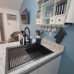 A kitchen with a black sink, white cabinets, and a blue wall.