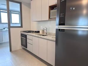 A modern kitchen with a stainless steel refrigerator, a built-in oven, and a granite countertop. - Modern apartment with ocean view and gourmet balcony. (Bertioga)