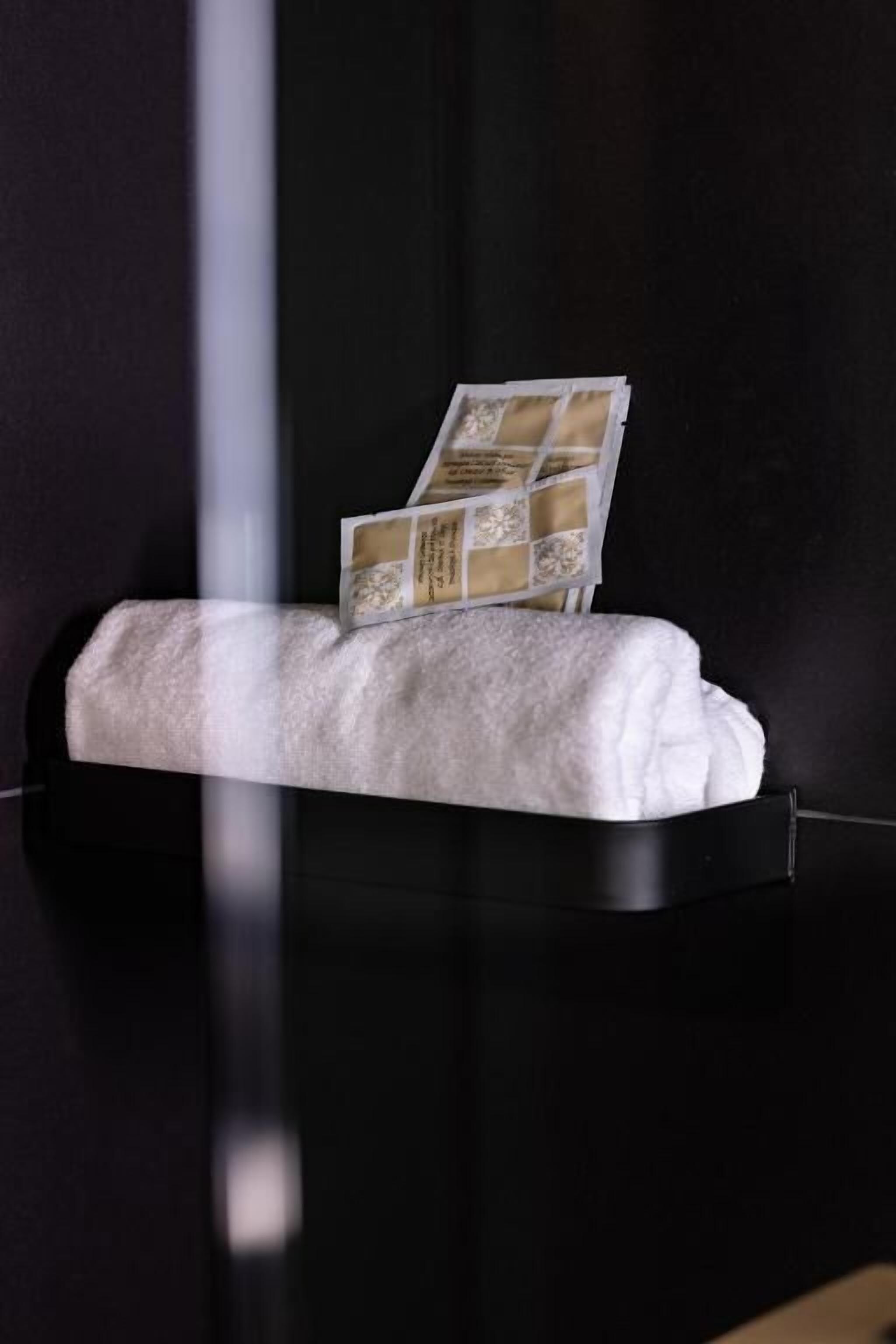 Un banco blanco acolchado con un atril para revistas frente a una pared oscura.