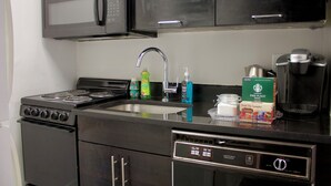 Uma cozinha equipada com fogão, micro-ondas, pia e cafeteira.