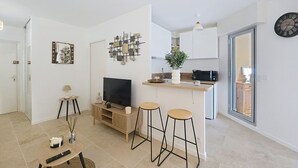 A modern living room with a TV, a small table, and two bar stools. - Cosy garden-floor studio - Sun & beach on foot (Golfe-Juan)