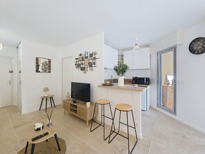 Un salon moderne avec un téléviseur, une petite table et deux tabourets de bar.